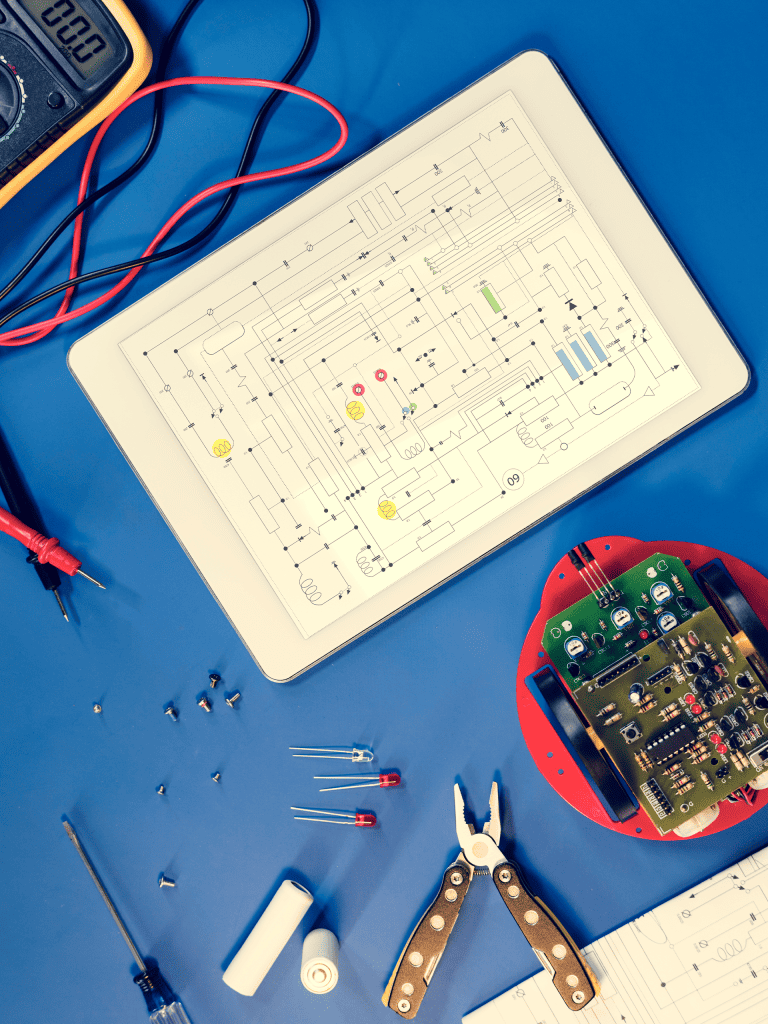 A tablet with a digital diagram rests on a blue mat with electrical equipment