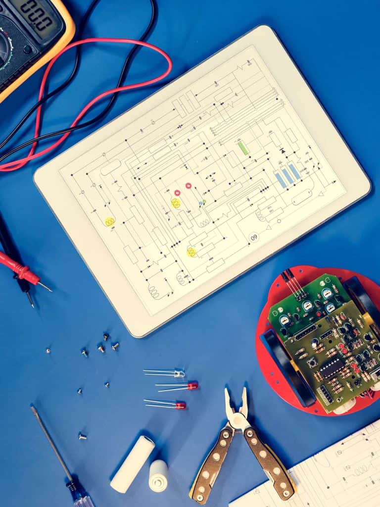 A tablet with a digital diagram rests on a blue mat with electrical equipment